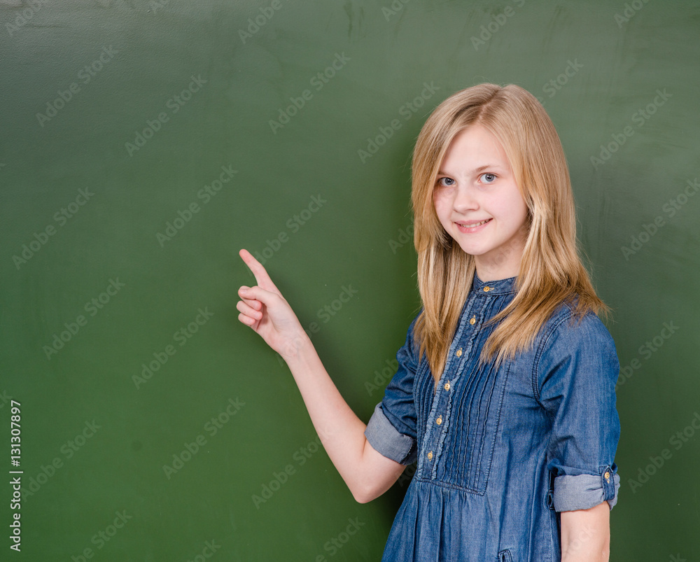 Young girl points on empty green chalkboard Young girl points on empty green chalkboard