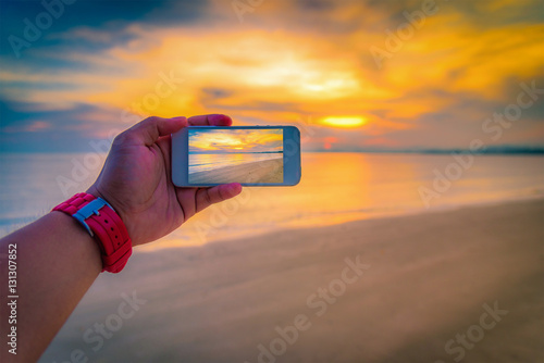 Man taking a picture of the sunset over sea harbor.