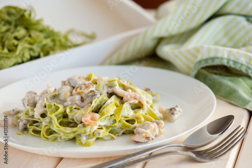 Sea foods and spinach fettuccine pasta on white dishes