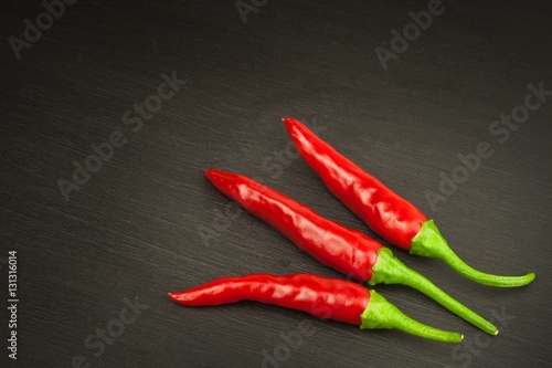 Red chilly pepper on wooden black background. Red hot chili peppers. Domestic cultivation extra hot chilli burn. Growing chili peppers. Spicy seasoning food. Healthy spices. 