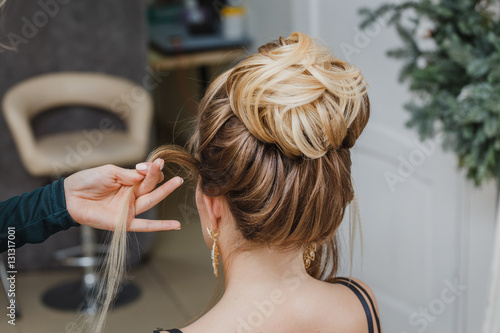 Hairdresser makes complex and beautiful hairstyle upper bun. Suitable for evening and wedding style