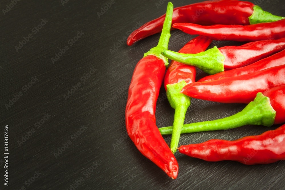 Red chilly pepper on wooden black background. Red hot chili peppers.  Domestic cultivation extra hot chilli burn. Growing chili peppers. Spicy seasoning food. Healthy spices.
