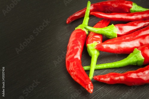 Red chilly pepper on wooden black background. Red hot chili peppers. Domestic cultivation extra hot chilli burn. Growing chili peppers. Spicy seasoning food. Healthy spices. 