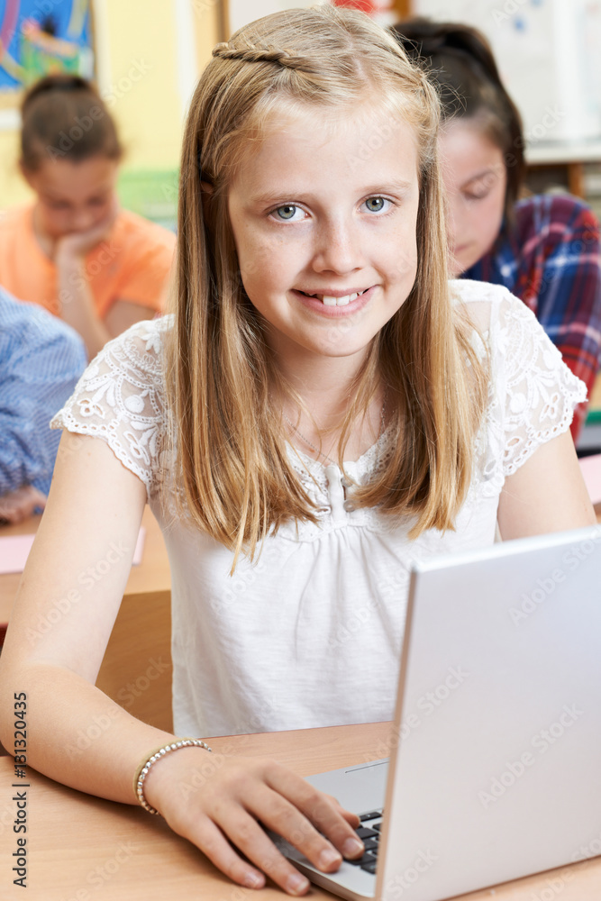 Female Elementary School Pupil Using Laptop In Computer Class