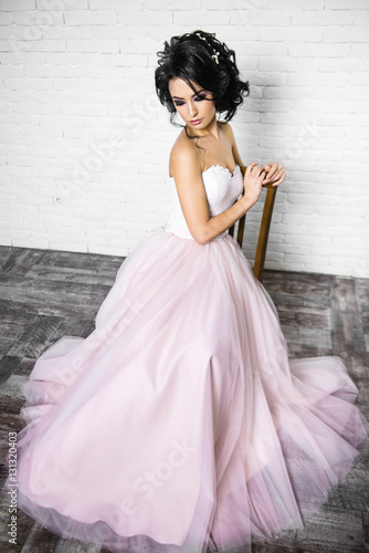 beautiful young brunette woman in a light pink long dress