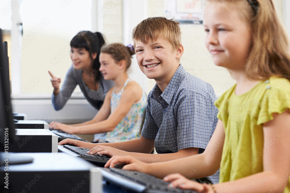 Male Elementary Pupil In Computer Class With Teacher