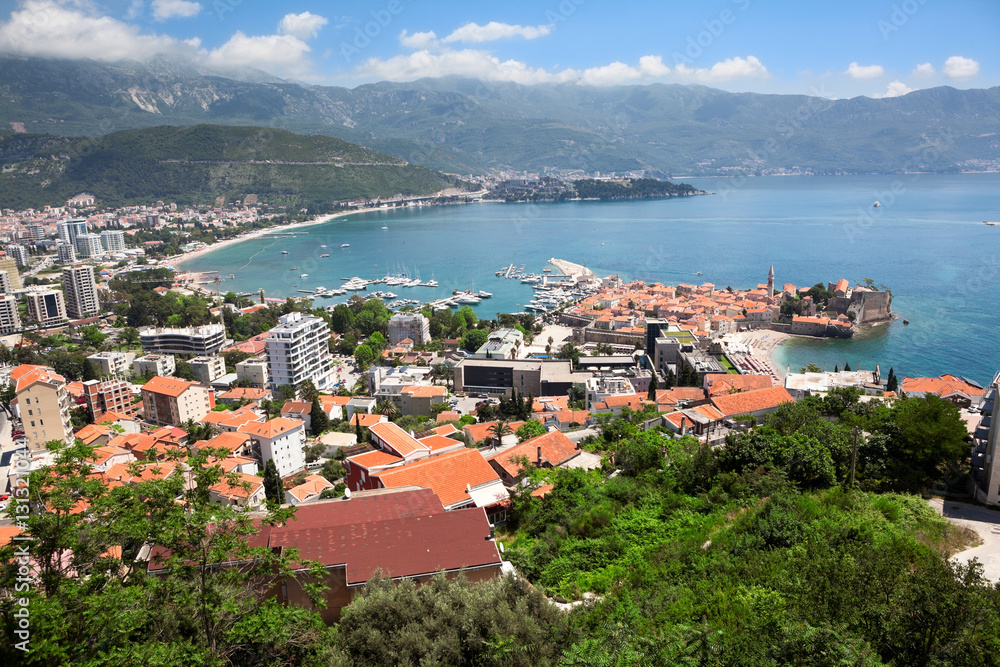 Aerial view at the Budva city with modern buildings, sea port and walled fortress. Montenegro, Europe