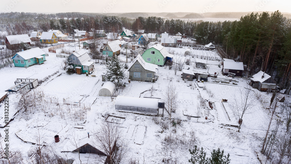 Obraz premium Timber houses and barns are covered with snow. Small agriculture earth lots are in coniferous wood. Karelia, Russia