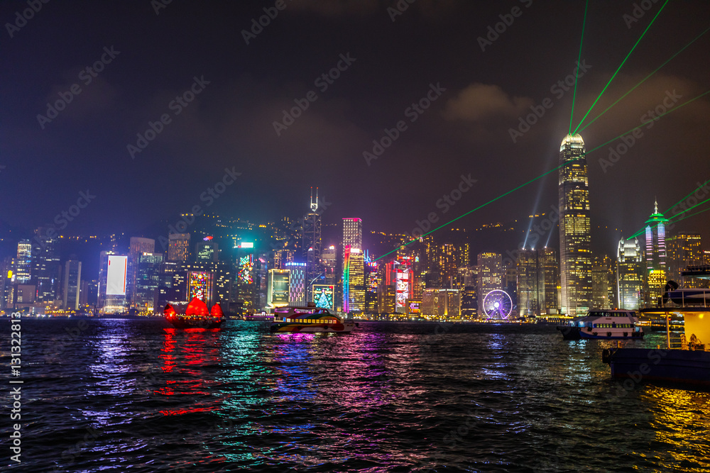 Naklejka premium Panoramę wyspy Hongkongu widzianą z nabrzeża Tsim Sha Tsui w Kowloon podczas pokazu Symfonia świateł z kolorowymi laserami wystrzelonymi z najsłynniejszych budynków w Hongkongu.
