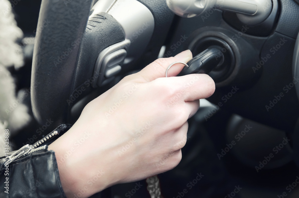 Closeup inside vehicle of hand holding key in ignition, start engine key