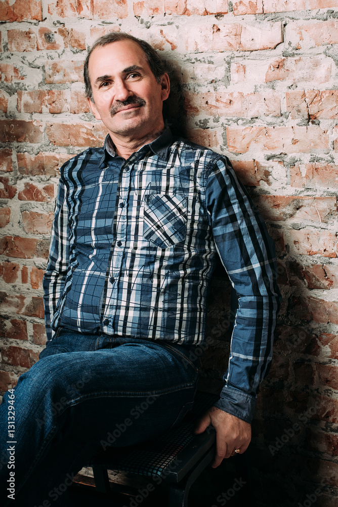 Handsome middle aged man is dressed in a casual clothing. Red brick wall background. Handsome middle aged man is dressed in a casual clothing. Red brick wall background.