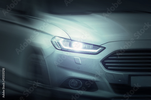 White sport car ride on road motion blur. Xenon and angel eyes headlamps