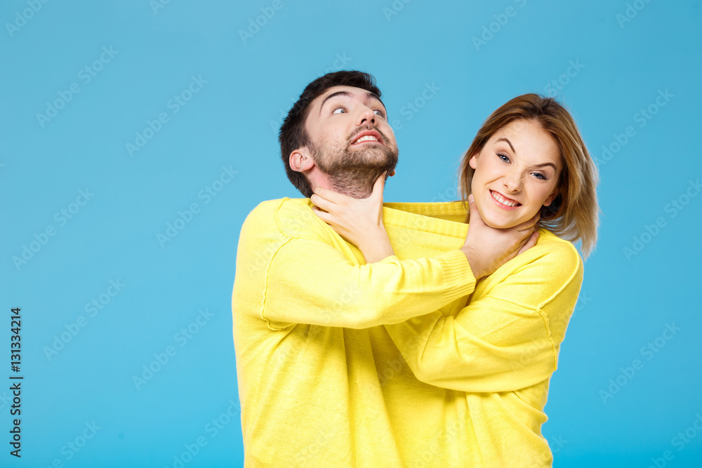 Young beautiful couple smohering each other over blue background. Young beautiful couple smohering each other over blue background.