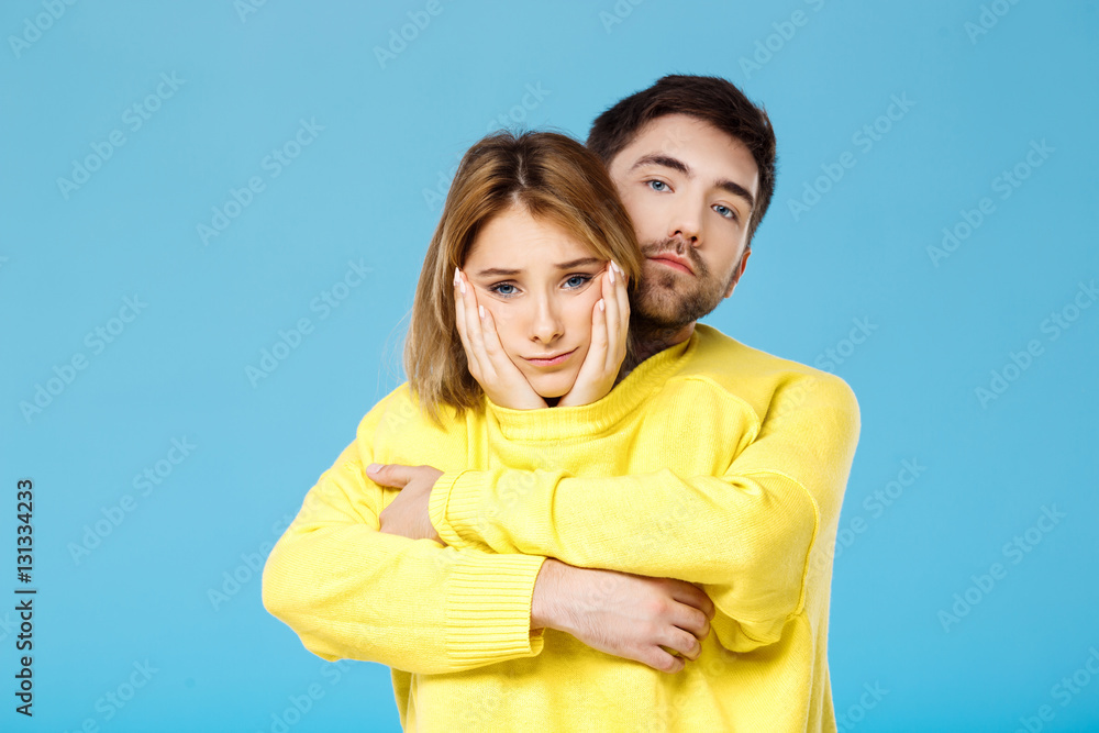 Young beautiful couple in one yellow sweater embracing smiling over blue background. Young beautiful couple in one yellow sweater embracing smiling over blue background.