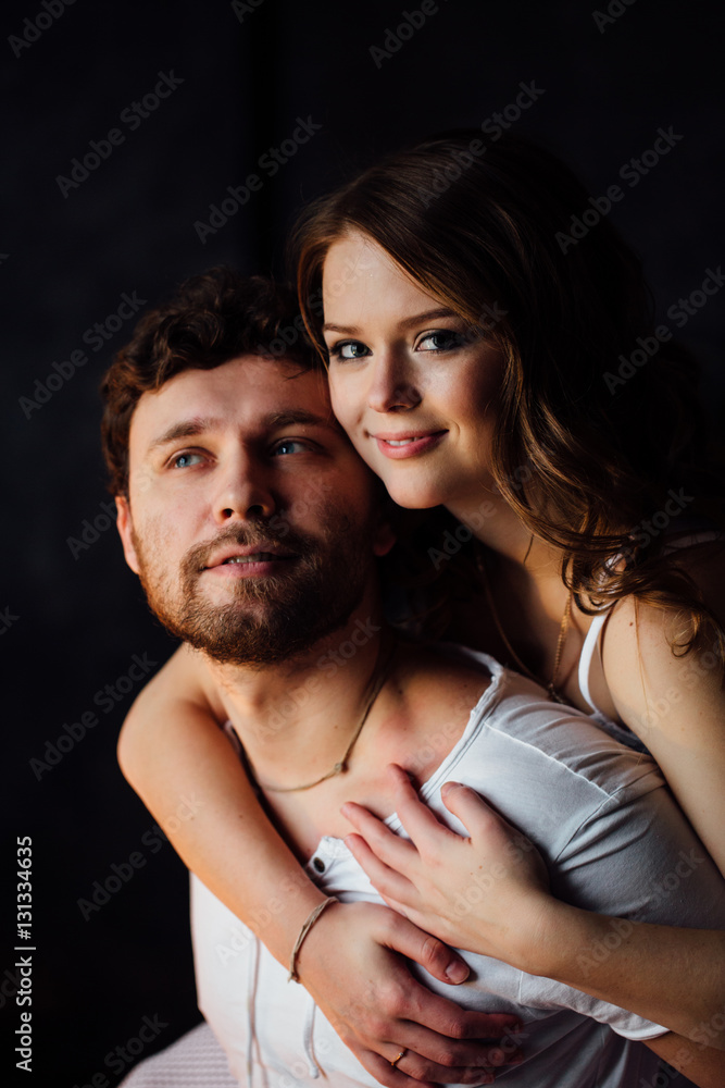 Happy couple of lovers in pajamas girl embracing man from behind. Happy couple of lovers in pajamas girl embracing man from behind.