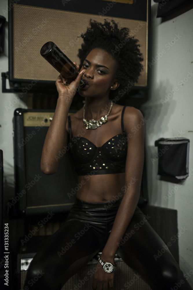 Portrait of young woman drinking beer in studio