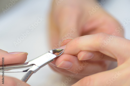 Tweezers being used on a woman's fingernail