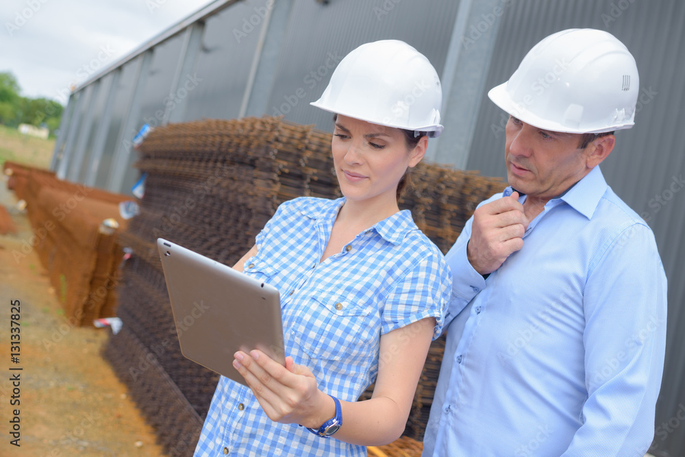 Two workers in hardhats looking at tablet Two workers in hardhats looking at tablet