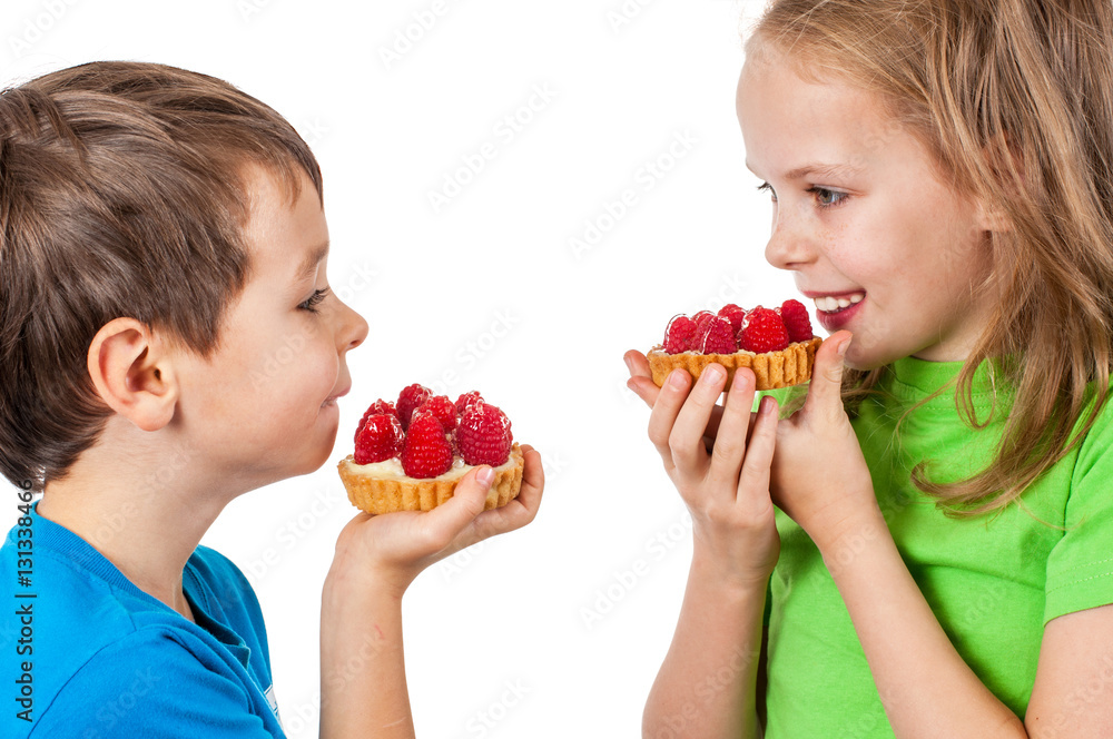 Little girl and boy eating cakes with fruits.