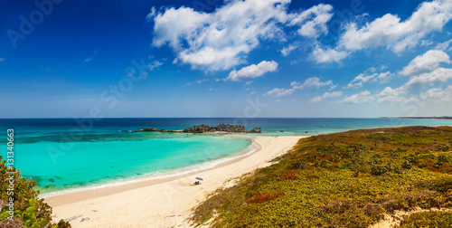 Fototapeta Naklejka Na Ścianę i Meble -  Dragon Cay at low tide, causeway mostly uncovered, and the curving white sand beach viewed from the cliffs above. Mudjin Harbor, Middle Caicos