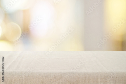 Empty table with linen tablecloth over blurred store with bokeh photo