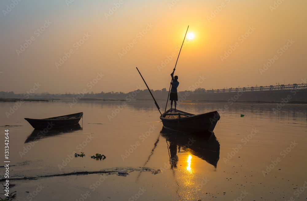 Fototapeta premium Silhouette boat with oarsman at sunset on river Damodar, Durgapur Barrage, West Bengal, India.