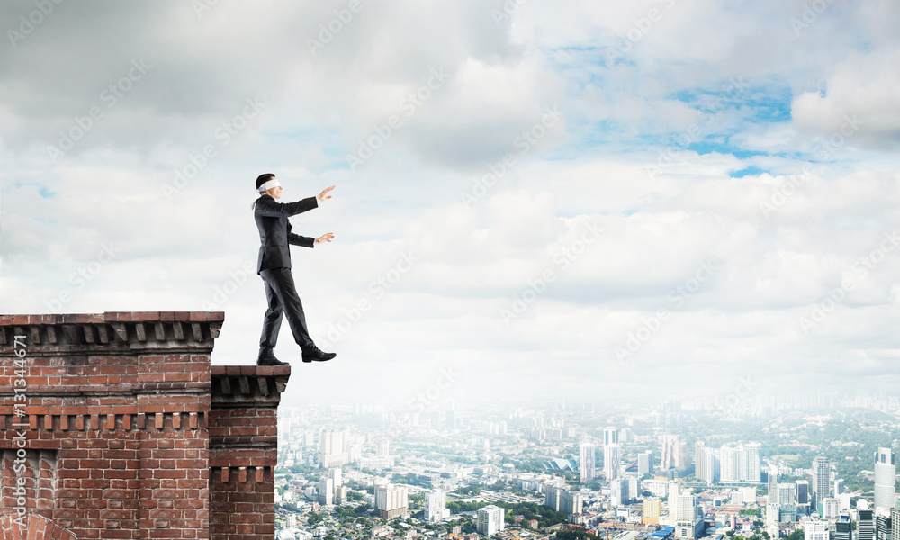 Danger and risk concept with businessman making step from edge Danger and risk concept with businessman making step from edge
