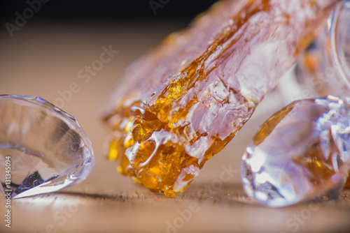 Piece of cannabis oil concentrate aka shatter with glass rig and photo