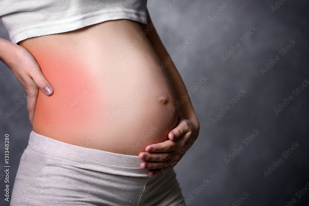 Pregnant woman with back ache on dark background Pregnant woman with back ache on dark background