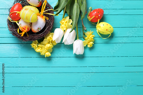 Decorative Easter eggs in nest and bright spring flowers