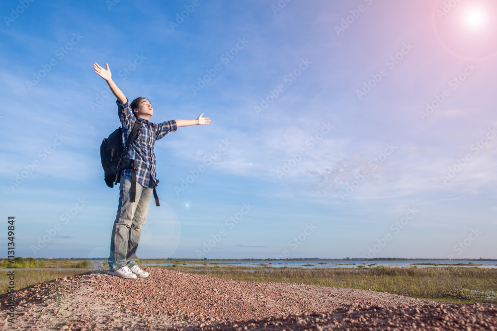 Young girl spreading hands with joy and inspiration facing the s