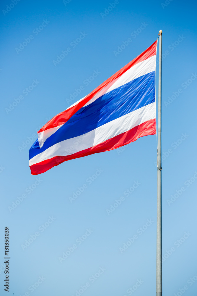 waving Thai flag of Thailand with blue sky background.