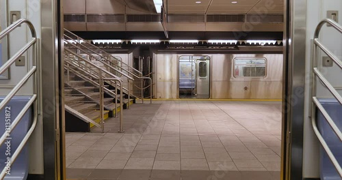 An interior view of the doors on a New York City subway car as they open at an empty platform.  	 photo