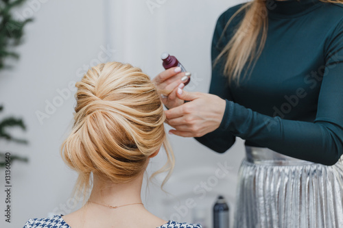 closeup of professional hairdresser hands doing beauty hairstyle a-la french twist