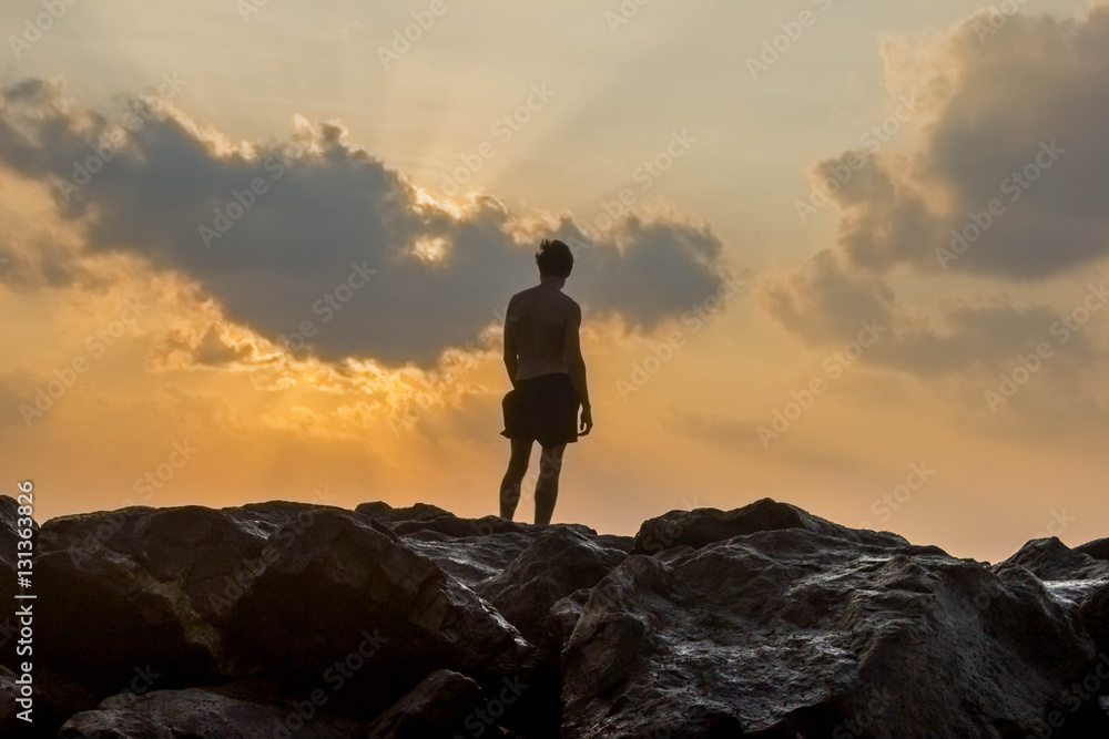 person standing on rocks seaside sunset silhouette frontback lig
