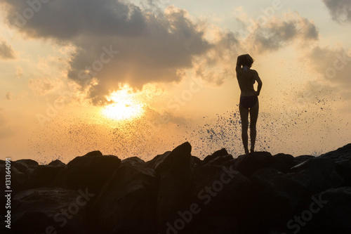 person standing on rocks seaside sunset silhouette frontback lig photo