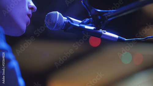 Young man sings to microphone in night club, close up photo