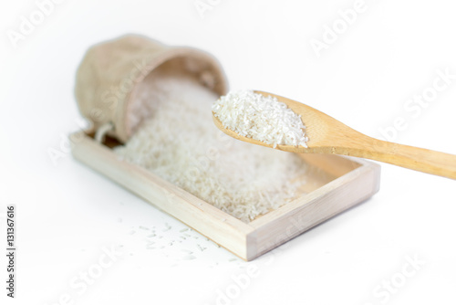 White long rice in a sack and wooden scoop isolated on white background photo