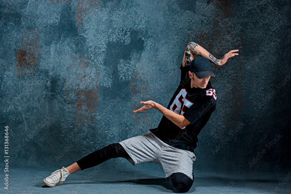 Young man break dancing on wall background.