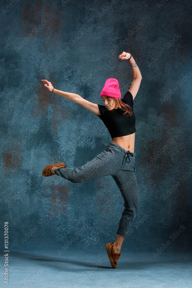 Young girl break dancing on wall background.