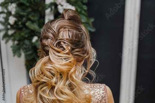 Rear view closeup of a hairdresser masterpiece of wavy and textured tail hairstyle in beauty salon
