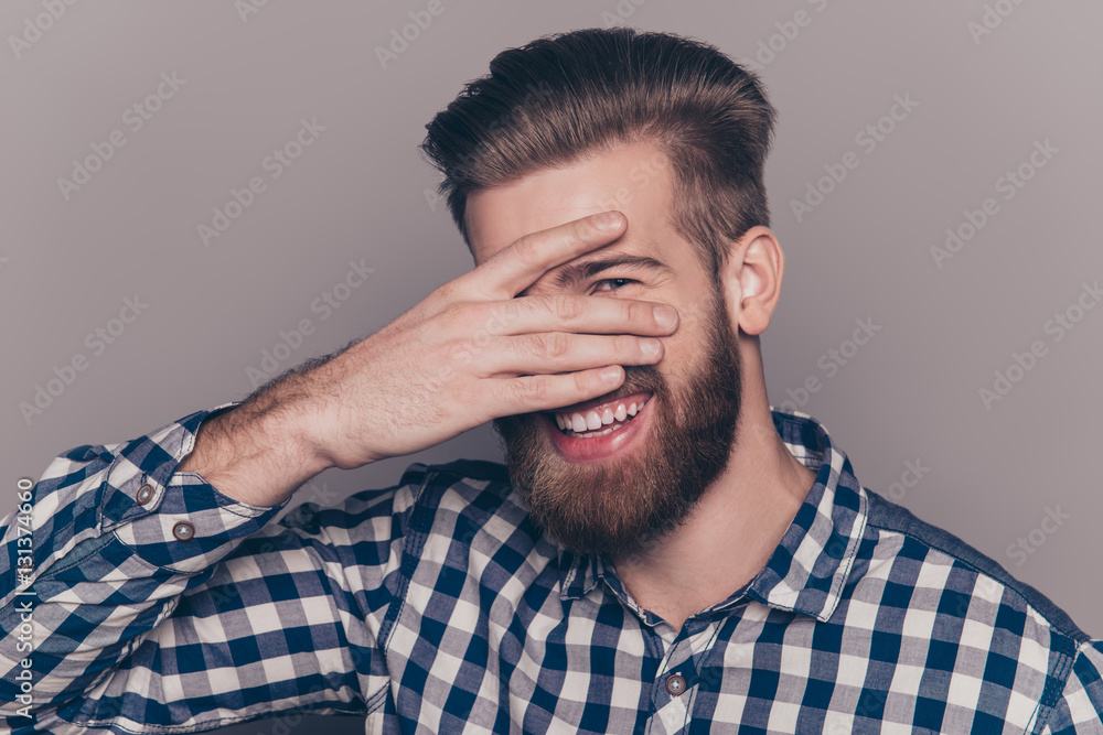 Funny cute young man with beard hiding his face with palms and s Funny cute young man with beard hiding his face with palms and s
