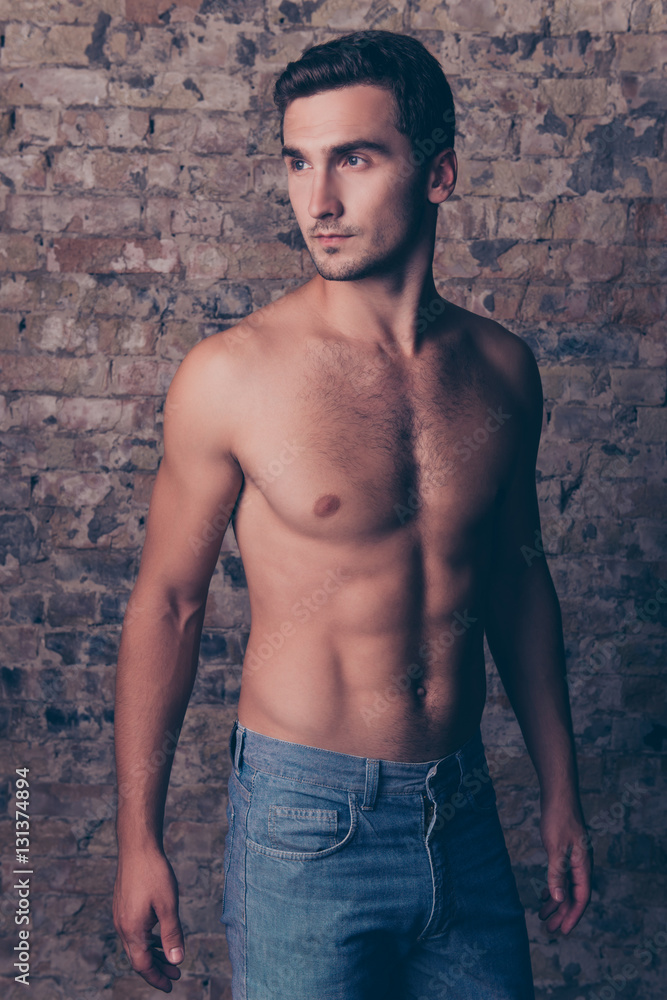 Fototapeta premium Strong athletic man standing on the brick wall background