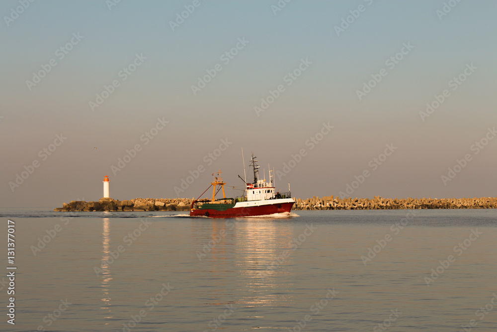 Small red fishing boat entering the port