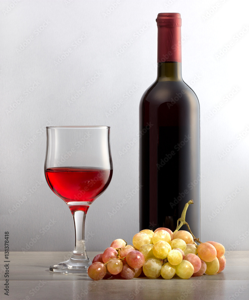 Виноградное красное вино в стеклянном бокале, гроздь винограда и бутылка вина для праздника.\ Натуральное виноградное вино для праздника, для здорового образа жизни.