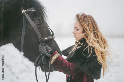 a girl with a horse in a field in winter