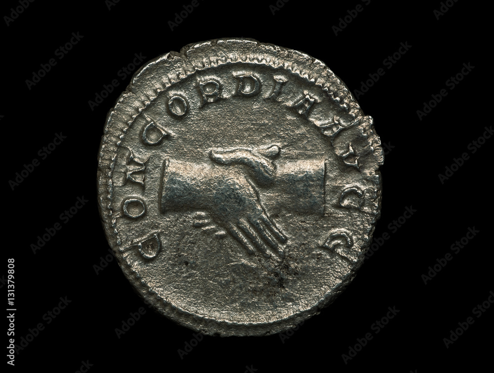 Ancient roman silver coin with image of handshake on it isolated on black