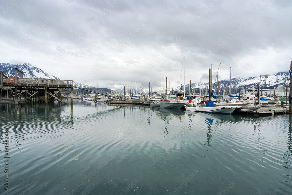 View of fishing boats moored at the port of Seward and snow covered mountains, Alaska