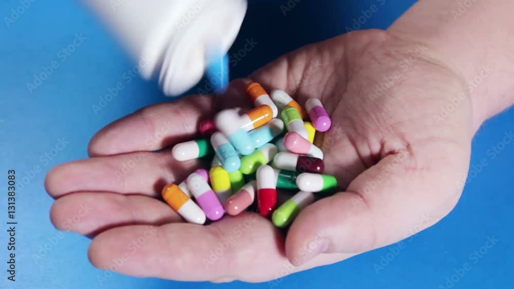 different colored pills poured on hand different colored pills poured on hand