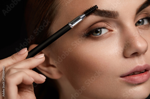 Beautiful Woman Brushing Eyebrows With Brush. Beauty photo